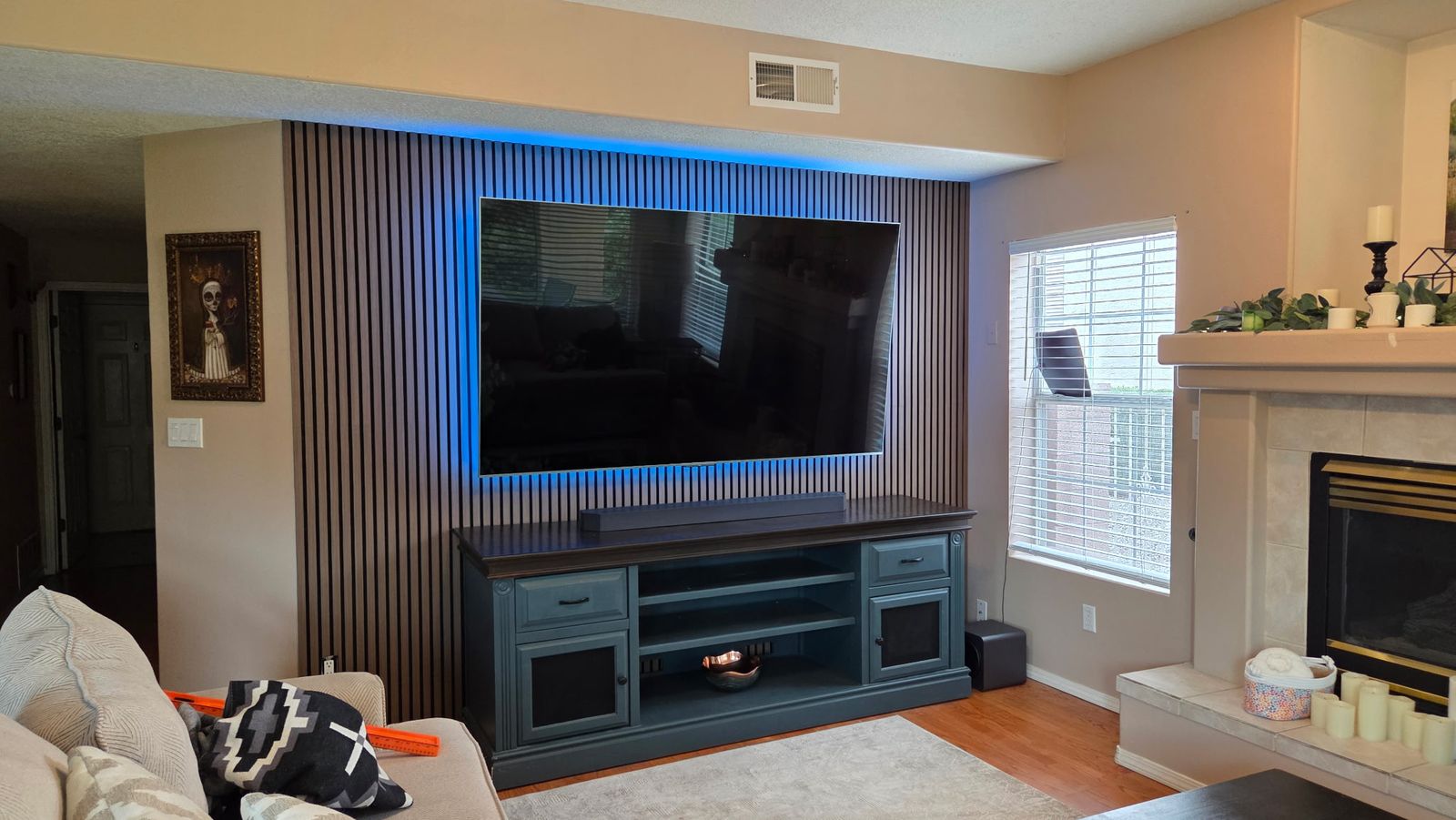 Large TV mounted on a wood slat accent wall with soft blue backlighting